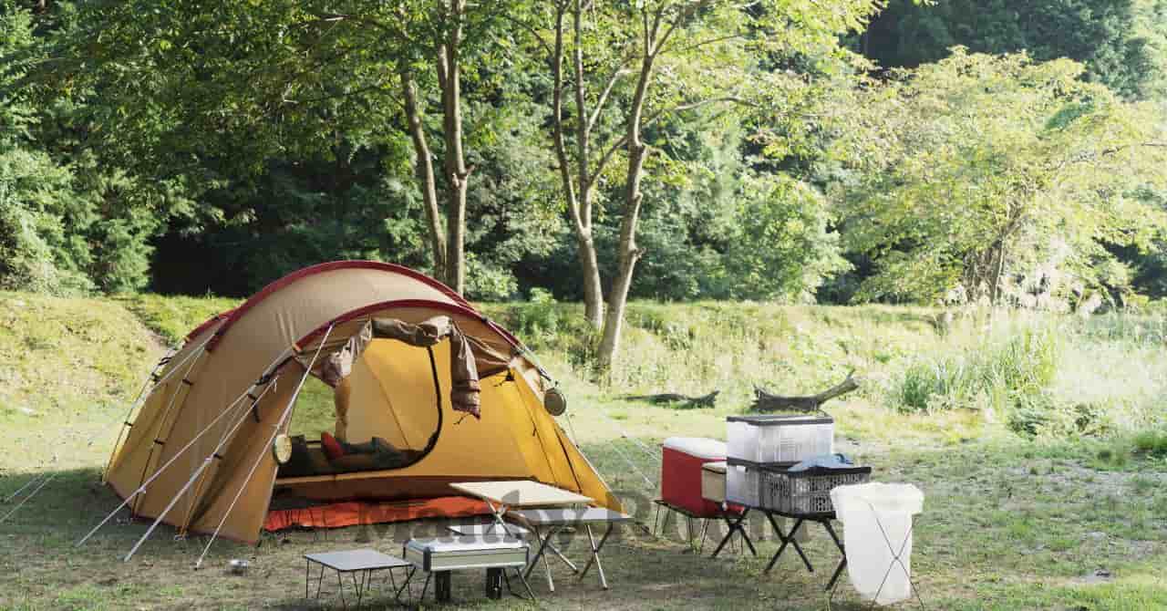 自然の中に設営されたテントとキャンプ用品が並ぶ静かなキャンプサイトの風景 