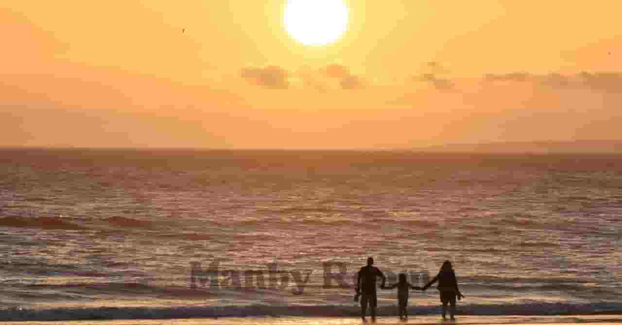 夕日が沈む海辺を歩く親子の後ろ姿。手をつないで歩く姿が、“特別な1日”の余韻とあたたかな親子の時間を感じさせるイメージ。