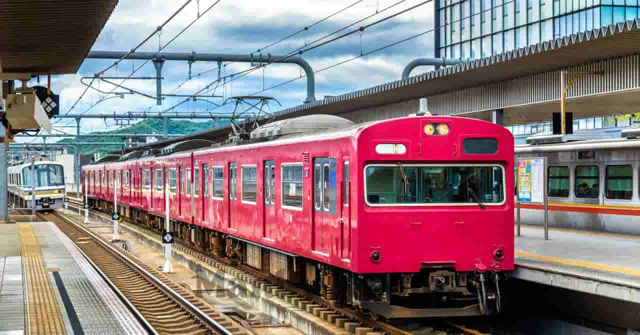 駅のホームに停車する赤い関西の電車。近畿エリアの移動や家族のおでかけをイメージさせる風景 