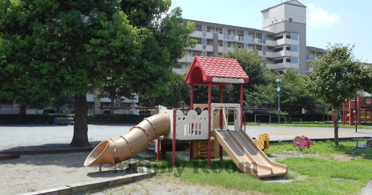 すべり台とトンネル付きの小型遊具がある住宅街近くの公園と木陰のある広場の様子
