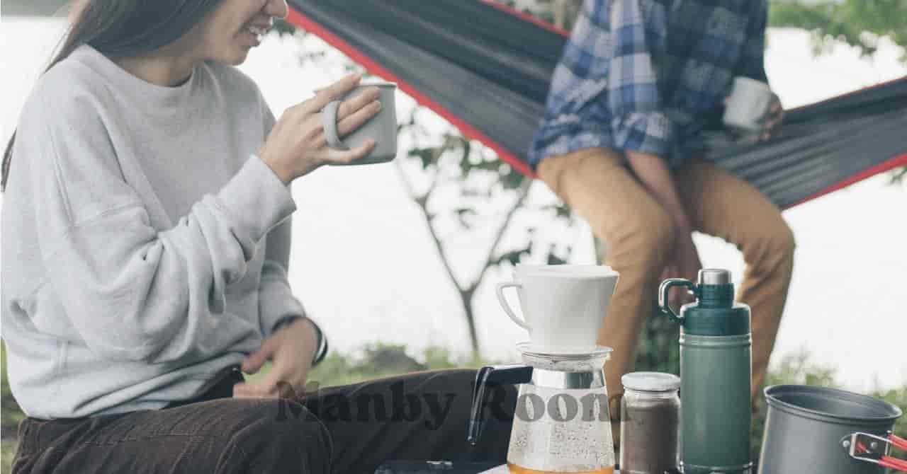 ハンモックでくつろぐ男性と笑顔でコーヒーを楽しむ女性、ゆるキャンプの穏やかな時間 