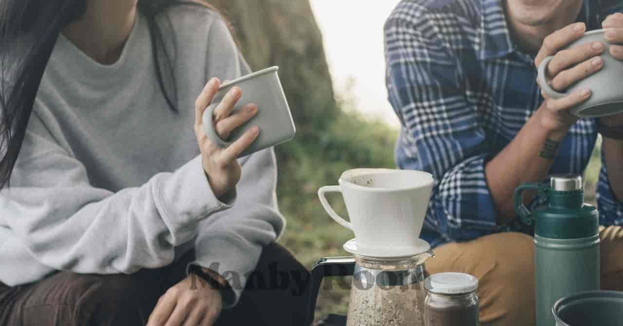 キャンプ場でコーヒーを淹れてくつろぐ男女の手元と笑顔の様子 