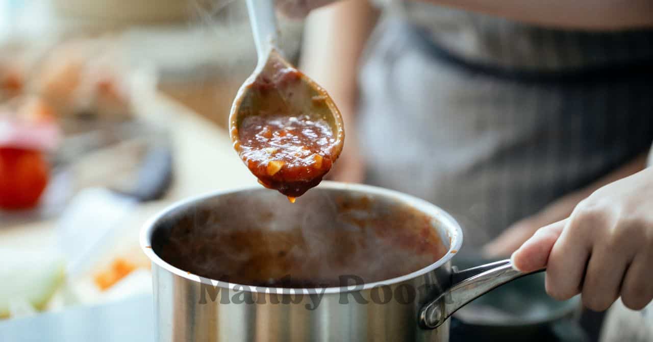 鍋を持ち、具だくさんのカレーをおたまですくい上げている様子